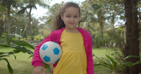 Cute Little Girl with a Soccer Ball in His Hand Smiling Looking at the Camera is Preparing to Play