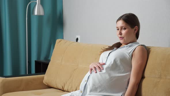 Pregnant Woman Doing Breathing Exercise Experiencing Contractions While Sitting on the Couch