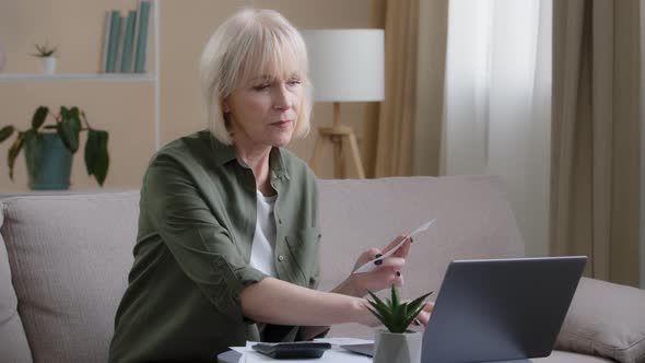 Serious Caucasian Old Senior Woman Sitting on Sofa Checking Financial Calculation Money Budget Bill