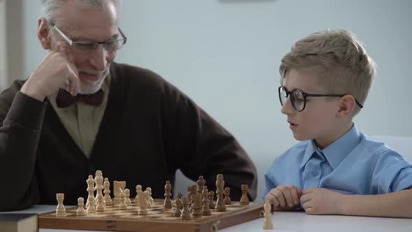 Smart Child Playing Chess With Grandfather, Family Having Fun, Early Development