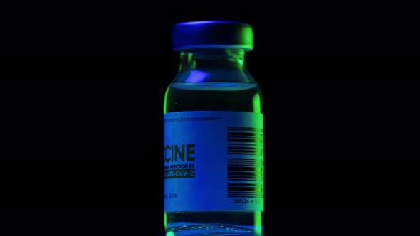 Vial of Vaccine for Coronavirus COVID19 Cure are Slowly Spinning Under Blue and Green Light