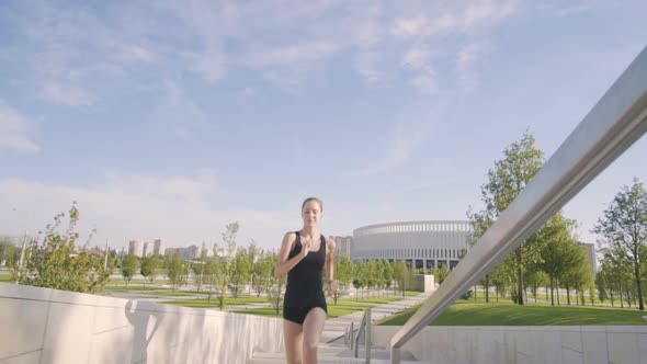 Sports Woman Makes Morning Jog and Physical Exercises In  Park