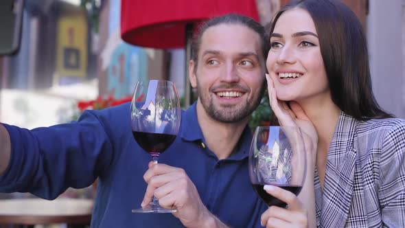 Happy Couple With Wine Taking Photos On Phone At Restaurant