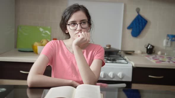 Girl Sitting Thinking at a Table in the Kitchen