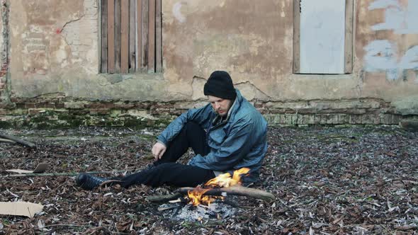 Homeless Man Sitting and Warming Himself By the Fire From Cold