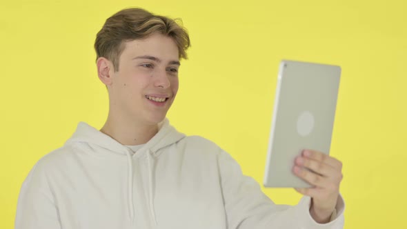 Video Chat on Tablet By Young Man on Yellow Background