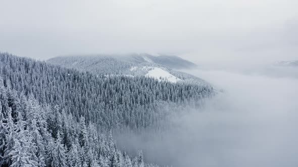 Aerial Cinematic view of Stormy clouds above Winter Mountains, Flying above Frozen Fores