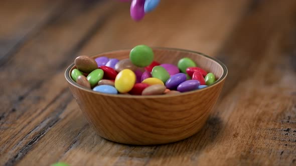 Slow motion, Colorful candies in a wooden bowl case isolated on wood background