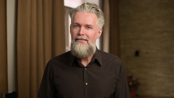 gray-haired bearded adult man listens attentively to something