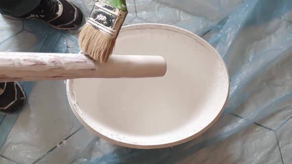 Home Improvements - cleaning a stick with a brush. The stick was used to stir the paint in the bucke