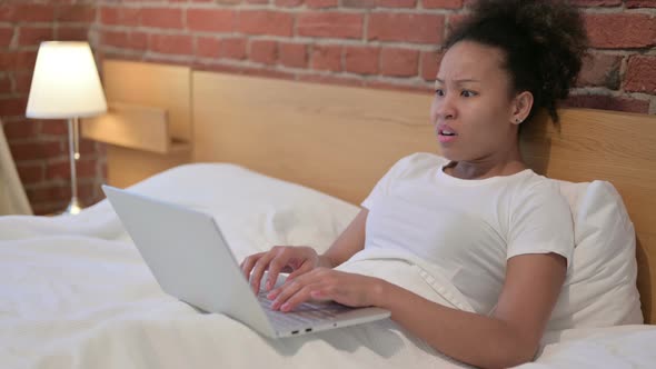 African Woman Reacting to Loss on Laptop in Bed