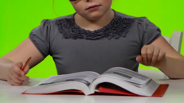 Girl Leafing Through a Book of Interesting Looks for Another. Green Screen. Close Up