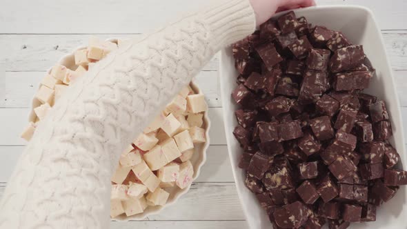 Flat lay. Step by step. Candy cane fudge cut in small cubes on a white serving dish.