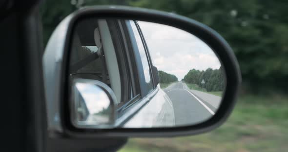 Closeup Side Rearview Mirror of Driving Car in Summer Day