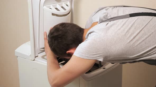 Employee Examines Top Loader of Washing Machine Near Wall