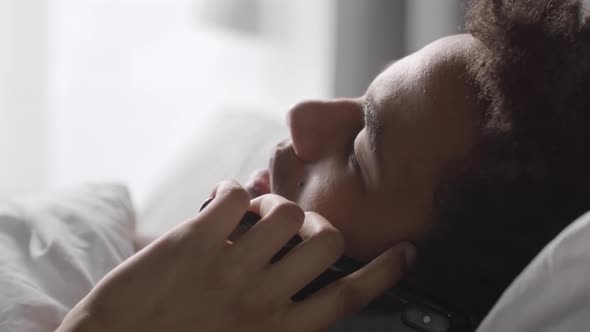 Black Man Talking on Phone in Bed