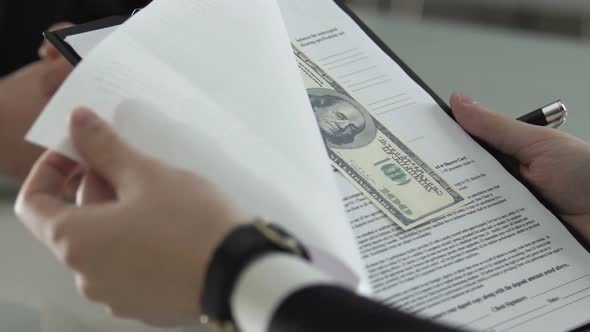 Man Signing Contract With Dollar Bills Inserted, Venality and Financial Crime
