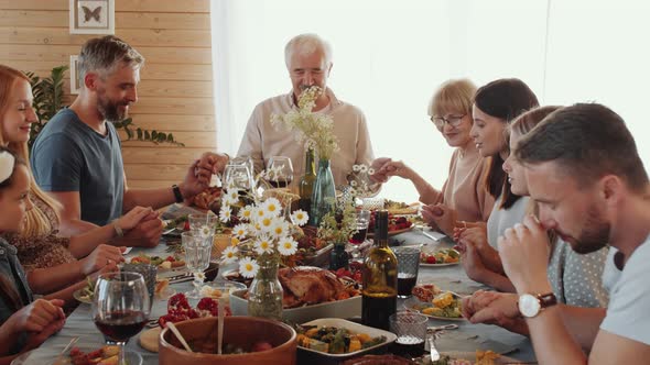 Large Caucasian Family Holding Hands and Praying before Meal