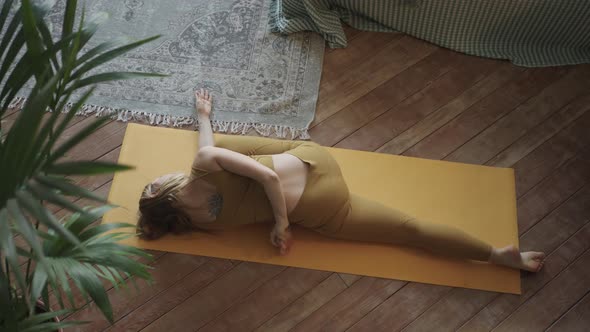 Slim Blonde Young Woman Does Yoga on Mat Lying on Floor