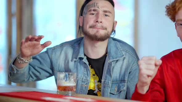 Portrait of Sport Fan with Tattoo on Face and Piercing Cheering for Team Watching Match with Redhead