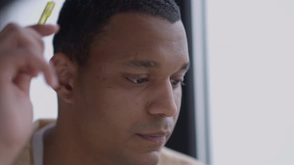 Closeup Face of Thoughtful Young Man Scratching Head with Pen Planning Business Idea in Home Office