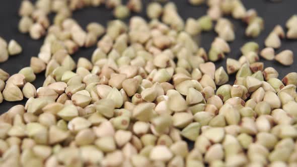 Bio product green buckwheat is poured in slow motion on a dark stone surface