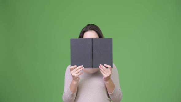 Young Beautiful Woman Hiding Behind Book