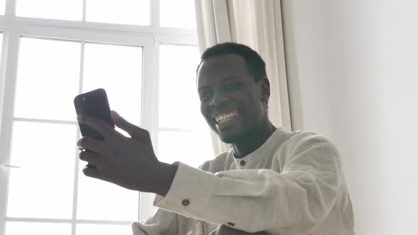 African American Man Communicates By Video Call on a Mobile Phone with His Friends or with His