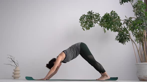 Attractive Curlyhaired Girl Practices Classical Yoga Assanas While Standing on the Mat at Home