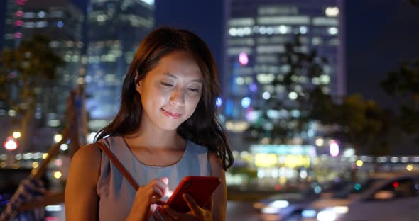 Woman use of mobile phone in city at night