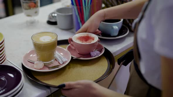 Female Waiter Is Putting Dessert and Two Mugs with Sweet Coffee on a Round Tray and Carrying It Over