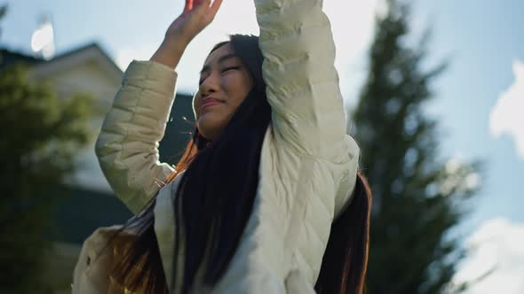 Joyful Cheerful Asian Young Woman in Headphones Dancing in Sunlight Spring Summer Garden Outdoors