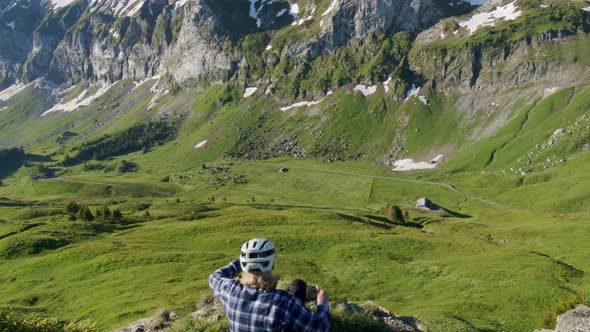 Mountain biker sits down and takes in the view from a ridge of abrupt mountains in front of him