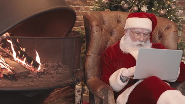 Santa Using Laptop by Fireplace