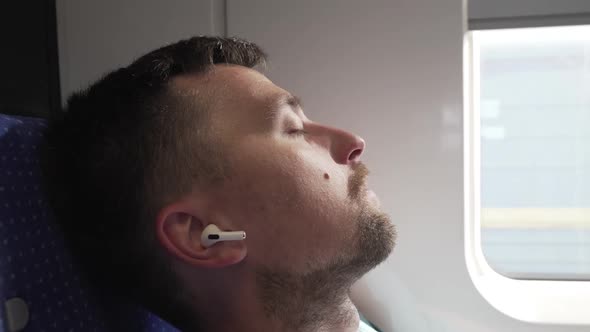 Casual Man with Earphones Getting Some Sleep on Long Train Journey