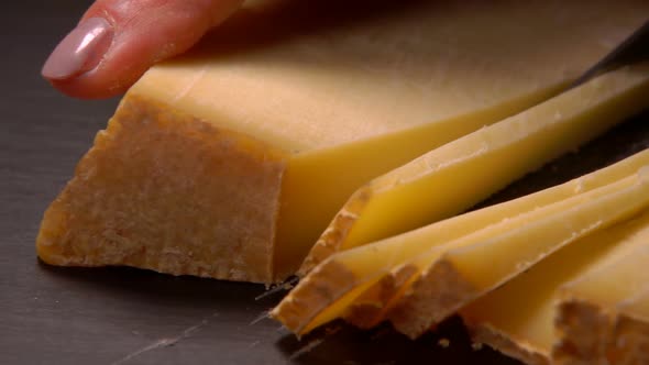 Hard Goat Cheese Is Cut with a Knife Into Pieces