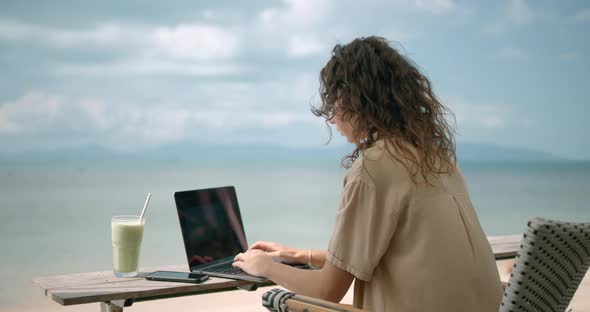 Women Seat at the Beach Bar and Works Freelance She Having Matcha Late Drink