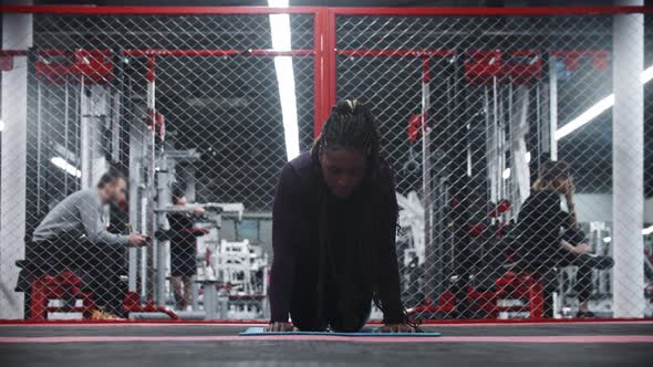 An Africanamerican Woman in the Gym  Standing on the Yoga Mat on Her Knees