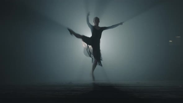 Diligent Young Graceful Ballerina Dancing Elements of Classical Ballet in the Dark with Light
