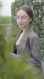 Vertical Video. Beautiful Girl in Glasses and a Gray Suit. Slow Motion