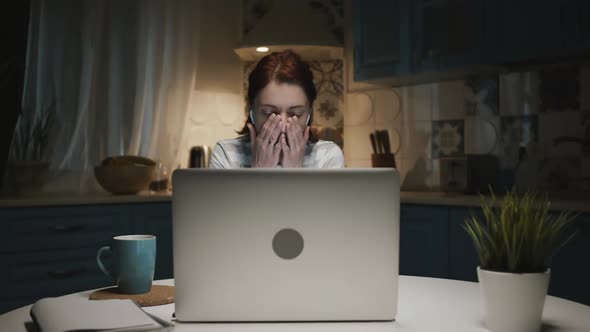 Woman In The Kitchen With Laptop. Woman Tired And Wants To Sleep. She Yawns