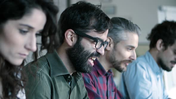 Side View of Smiling Developer in Eyeglasses Working with Laptop