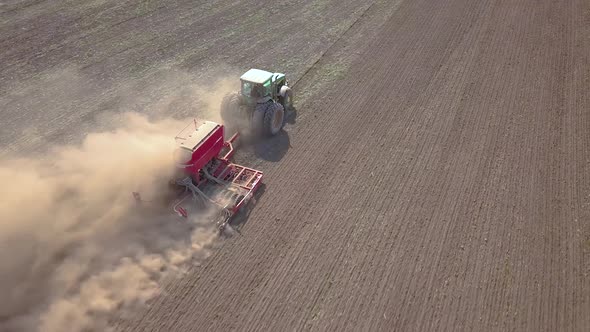 Top Down Aerial View of Green Tractor Cultivating Ground and Seeding a Dry Field