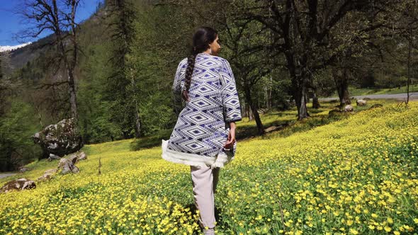 a Young Woman Is Walking Along the Field Past the Flowers in the Summer