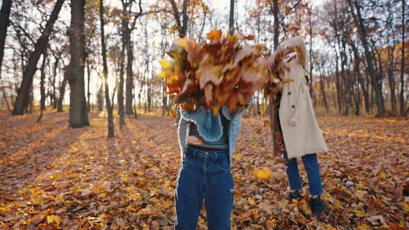 Young Parents and Their Kid Girl Laughing Jumping and Throwing Up Yellow Foliage While Playing in