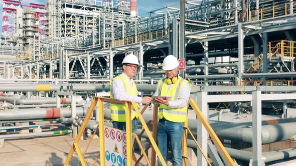 Industrial Workers are Having a Talk Among Refinery Constructions