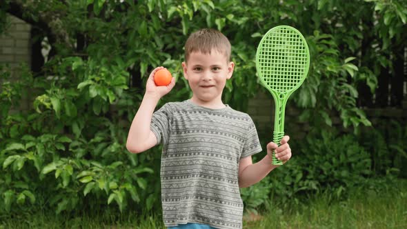 Portrait cute little smiling boy child with tennis racket and ball