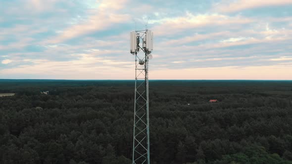 Aerial View of the 5G Antenna Rising Above the Road and Fields with Trees. Country Side. Parallax