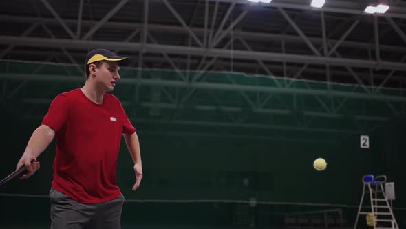 Adult Man is Playing Tennis on Indoor Court Hitting Ball By Racquet Professional or Amateur Training