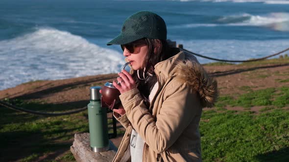 woman drinking mate, typical Argentine drink, on the beach, watching the sunset pichilemu, chile.